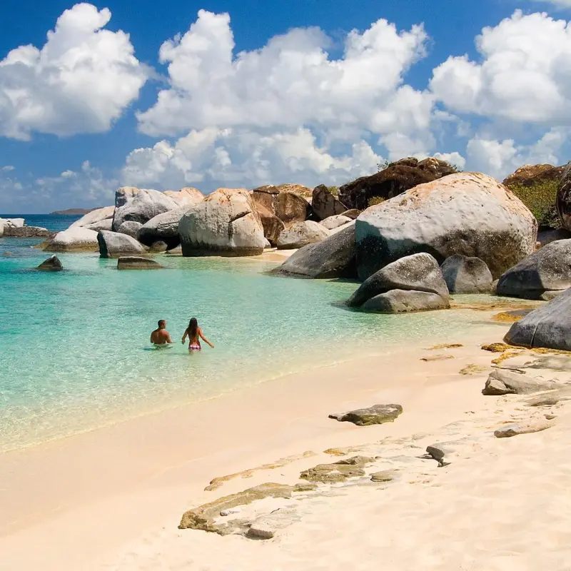 a group of people on a rocky beach with Virgin Gorda in the background