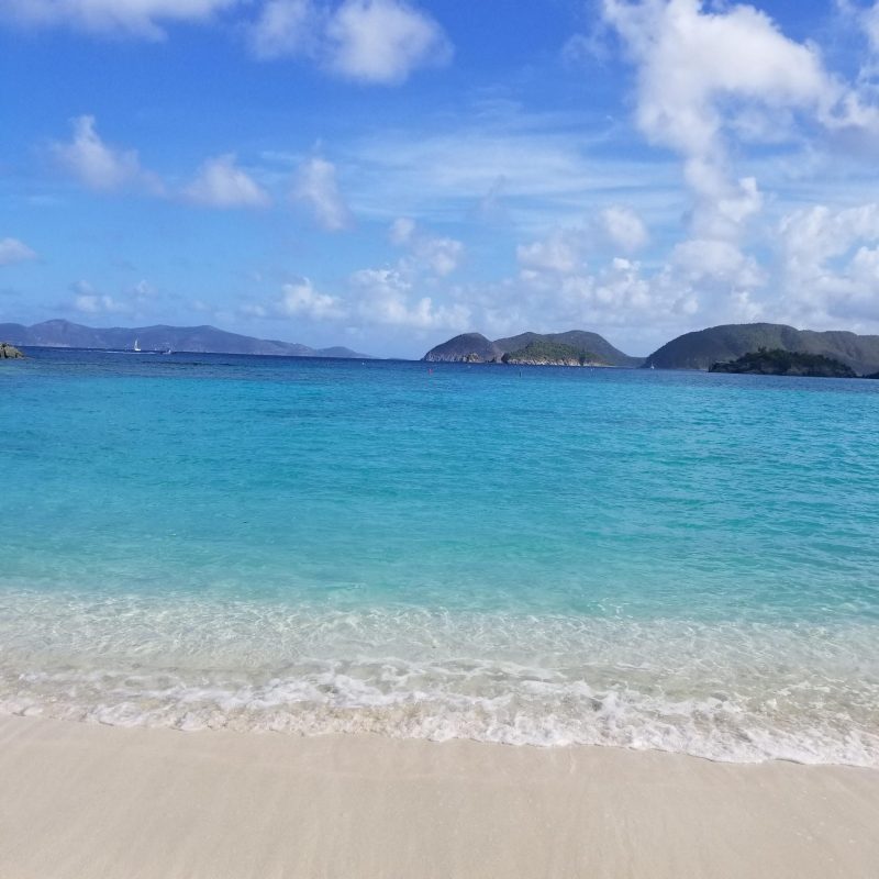 a sandy beach next to a body of water