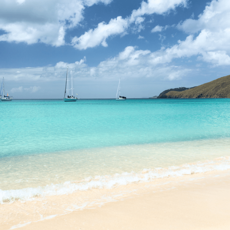 a boat sitting on top of a sandy beach next to the ocean