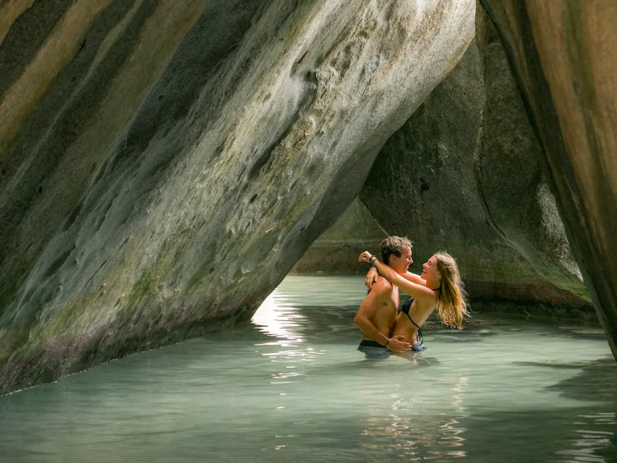 a person talking on a cell phone in the water with Virgin Gorda in the background