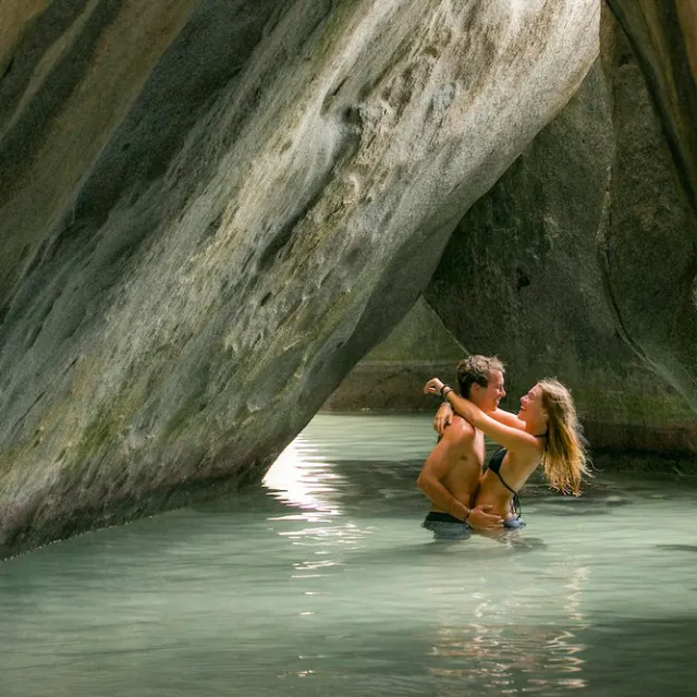 a person talking on a cell phone in the water with Virgin Gorda in the background