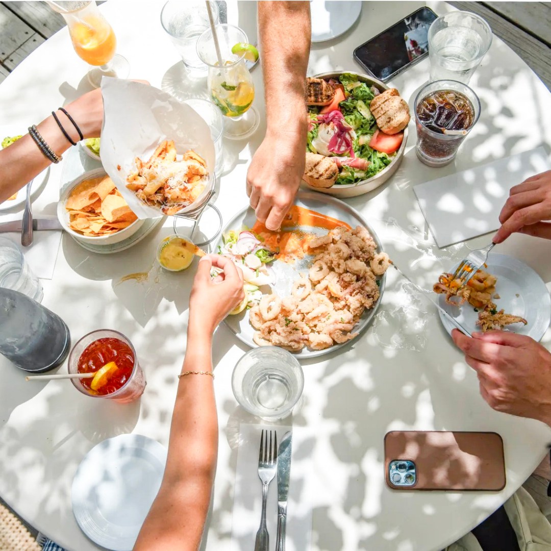 a group of people sitting at a table with food