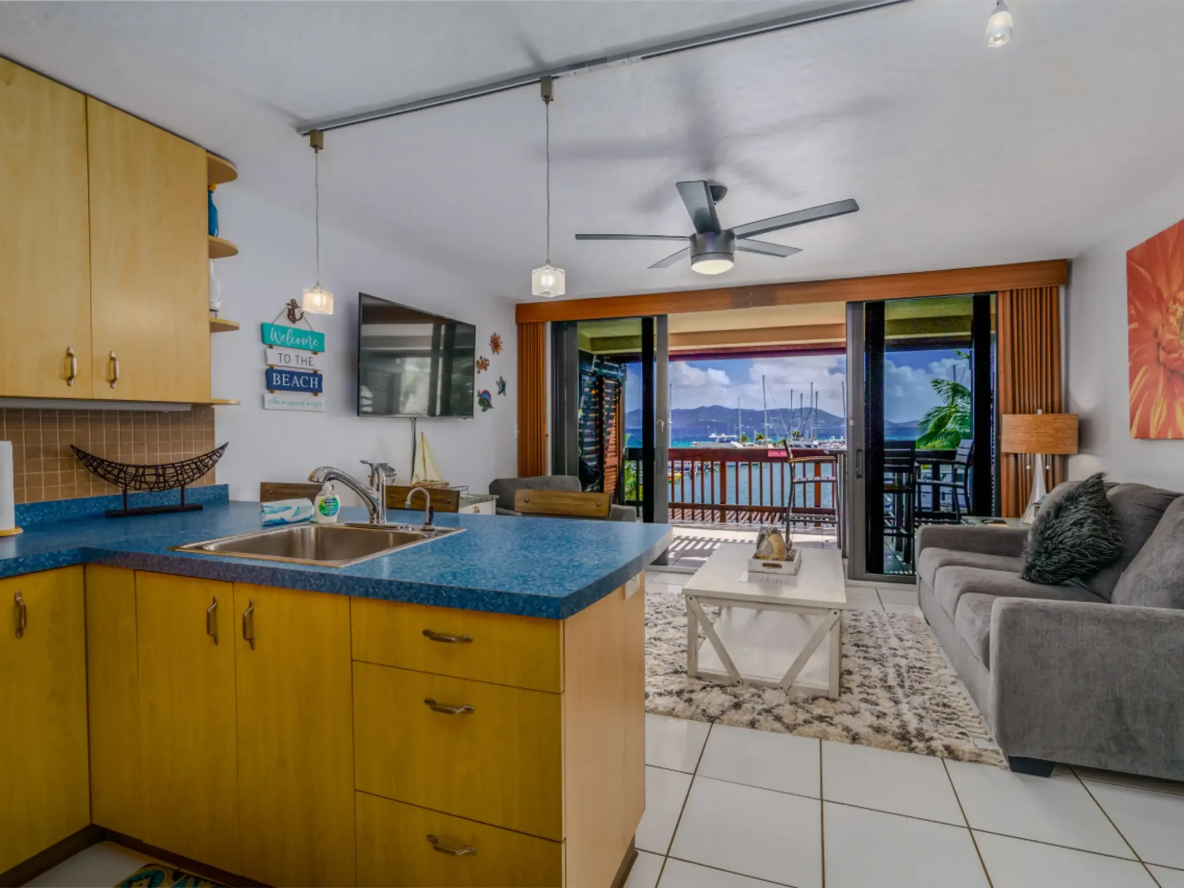 Open-plan kitchen and living room with balcony view of marina and boats.