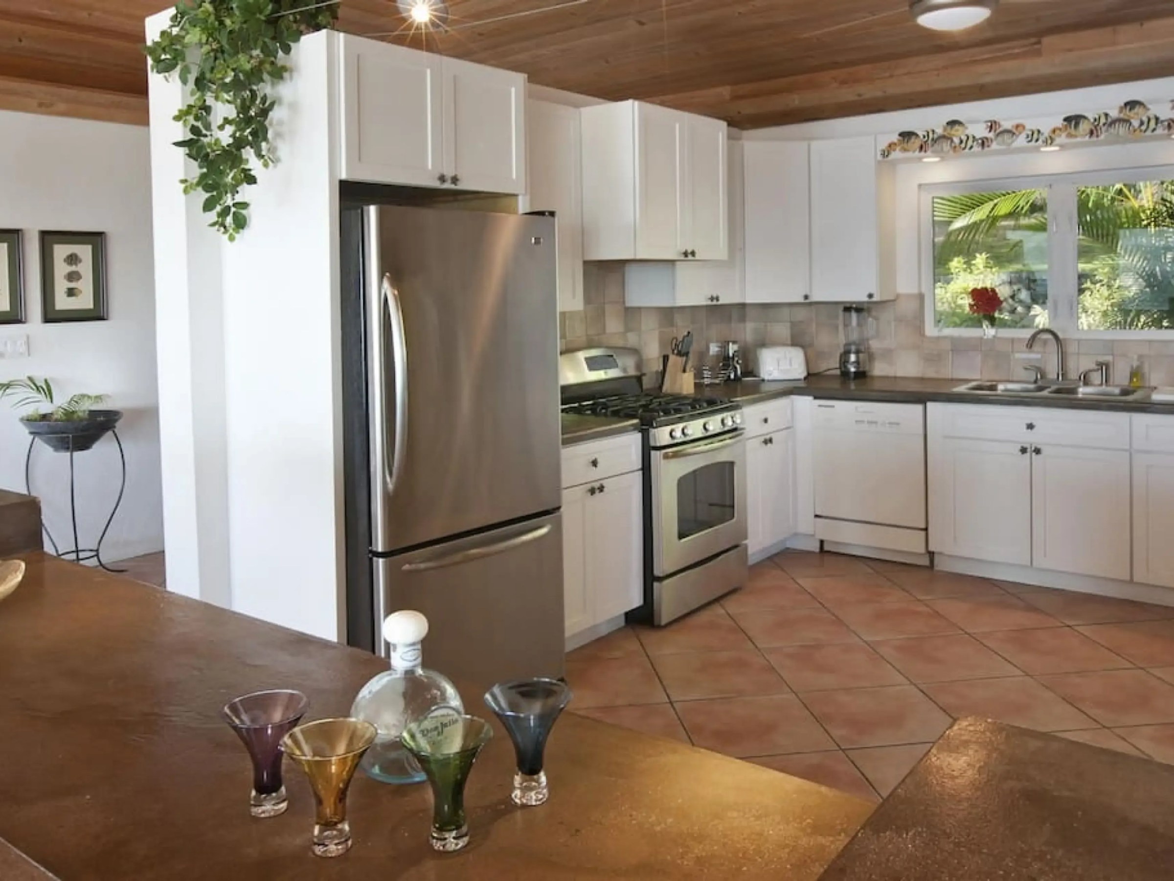 Modern kitchen with stainless steel appliances, white cabinets, and tiled floor.