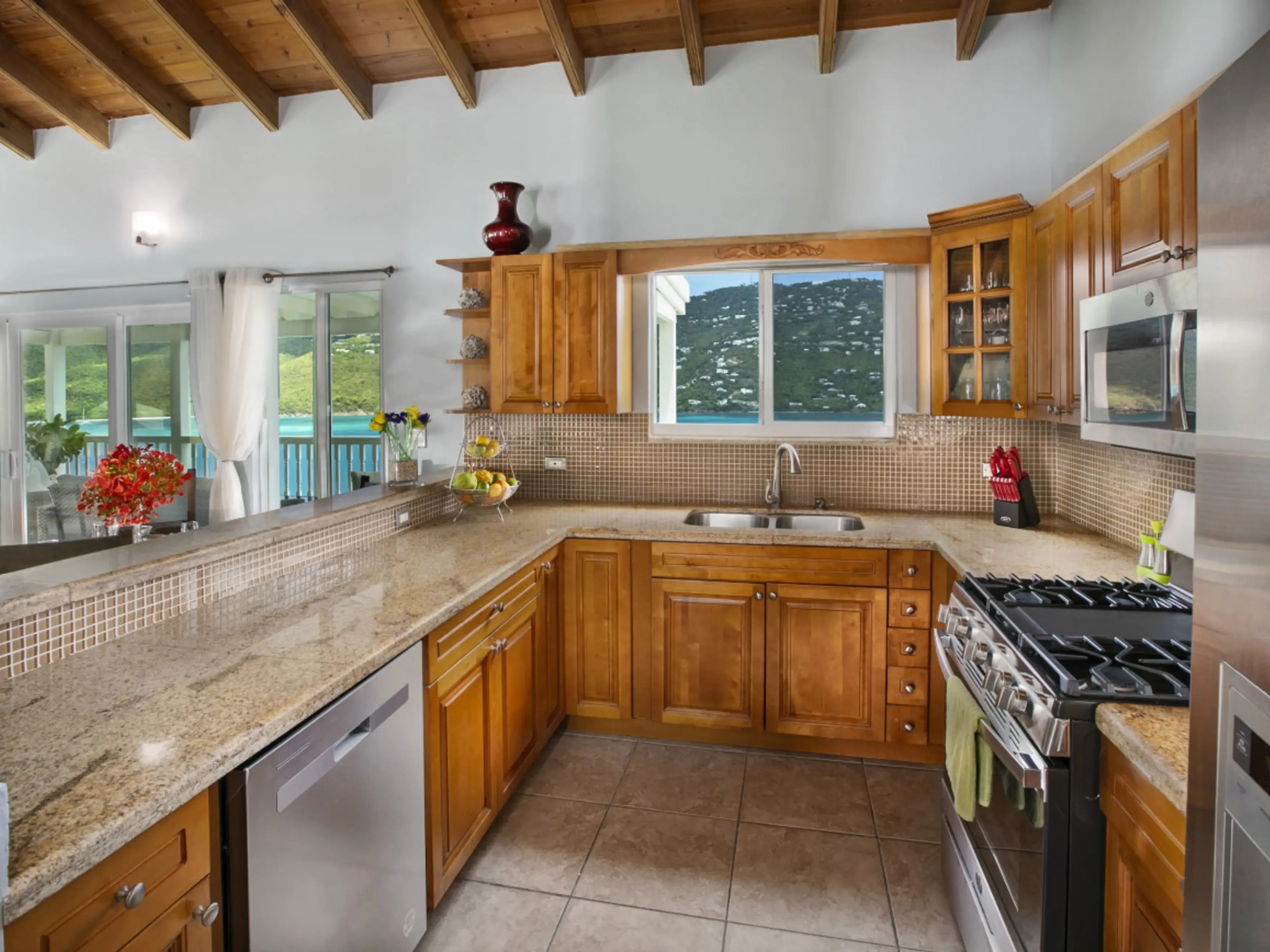 Modern kitchen with wood cabinets, granite countertops, and mountain view through window.