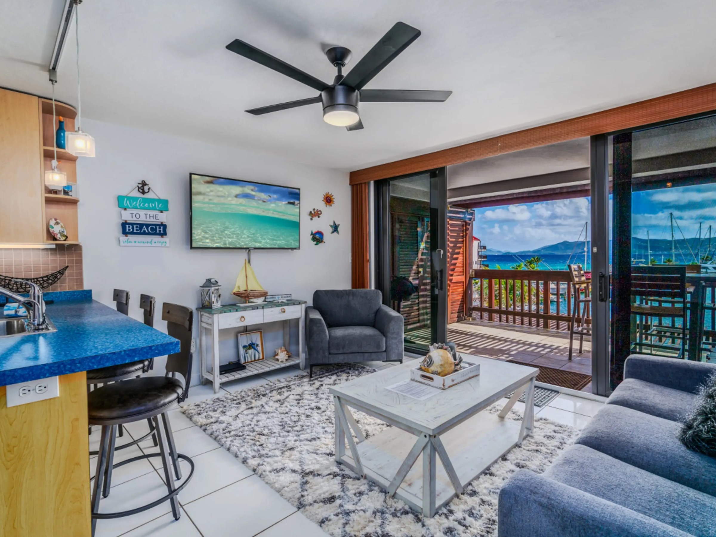 Cozy living room with ocean view, grey sofas, blue countertop, and nautical decor.