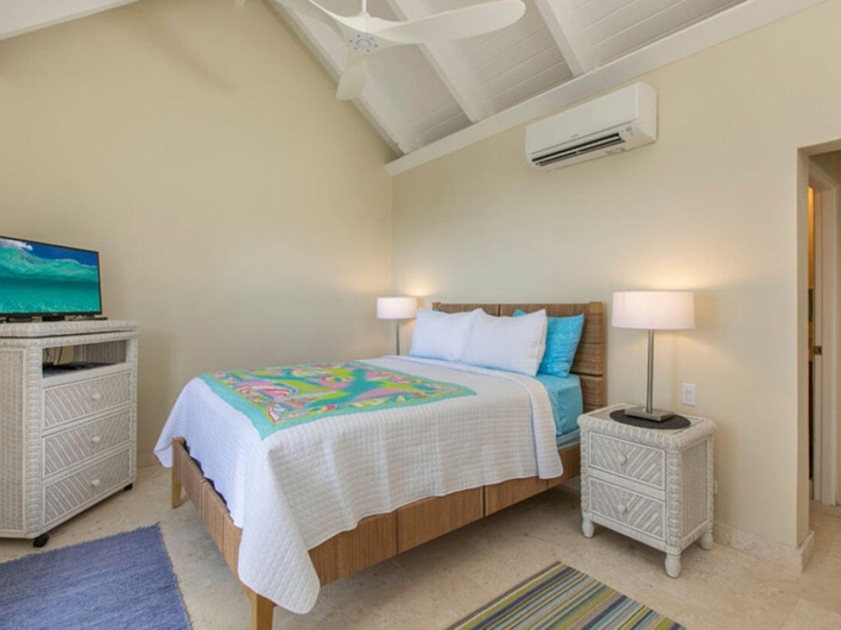 Bedroom with a bed, nightstands, TV, ceiling fan, and white vaulted ceiling.
