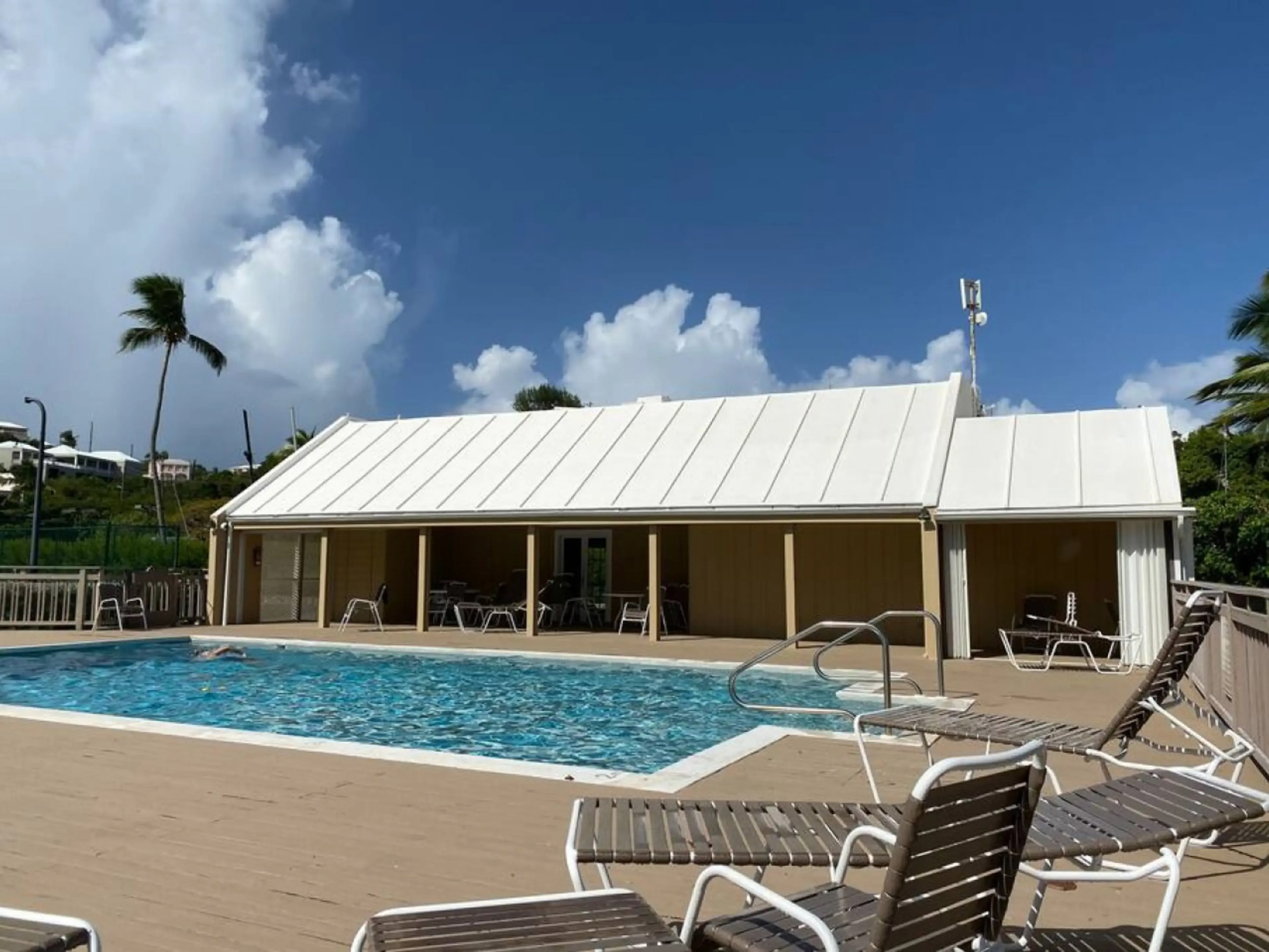 Outdoor pool area with sun loungers and a covered pavilion under a clear blue sky.