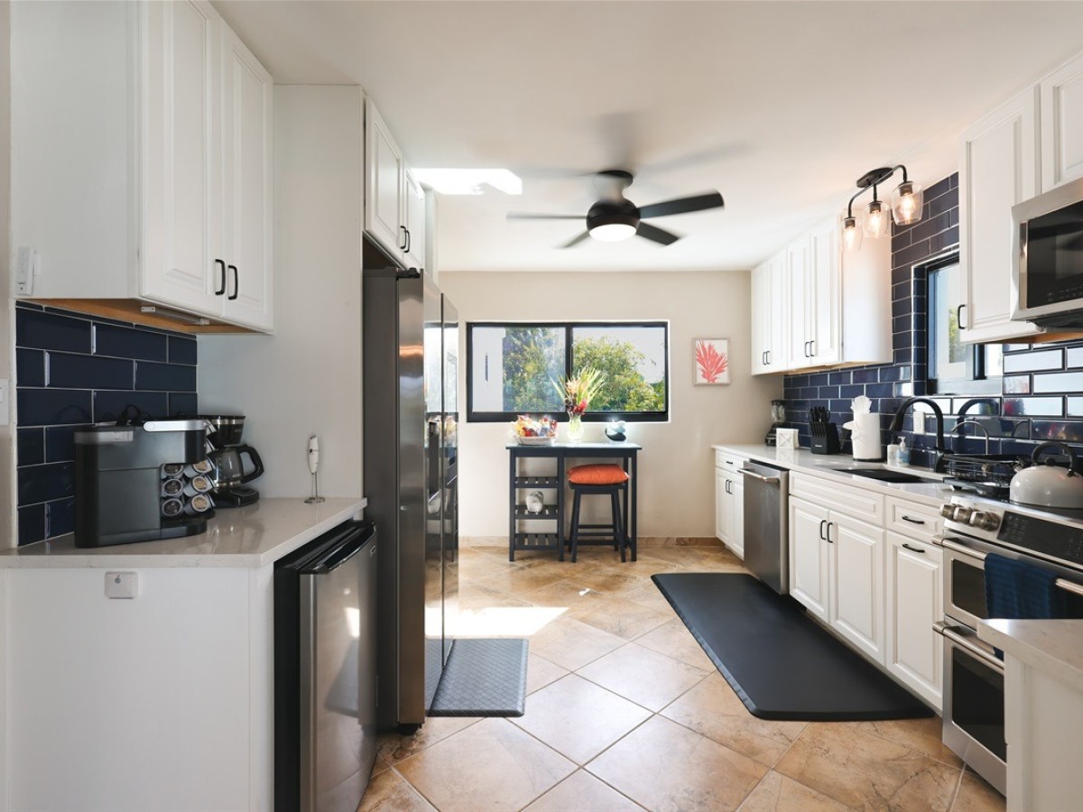 Modern kitchen with white cabinets, black appliances, and navy backsplash.