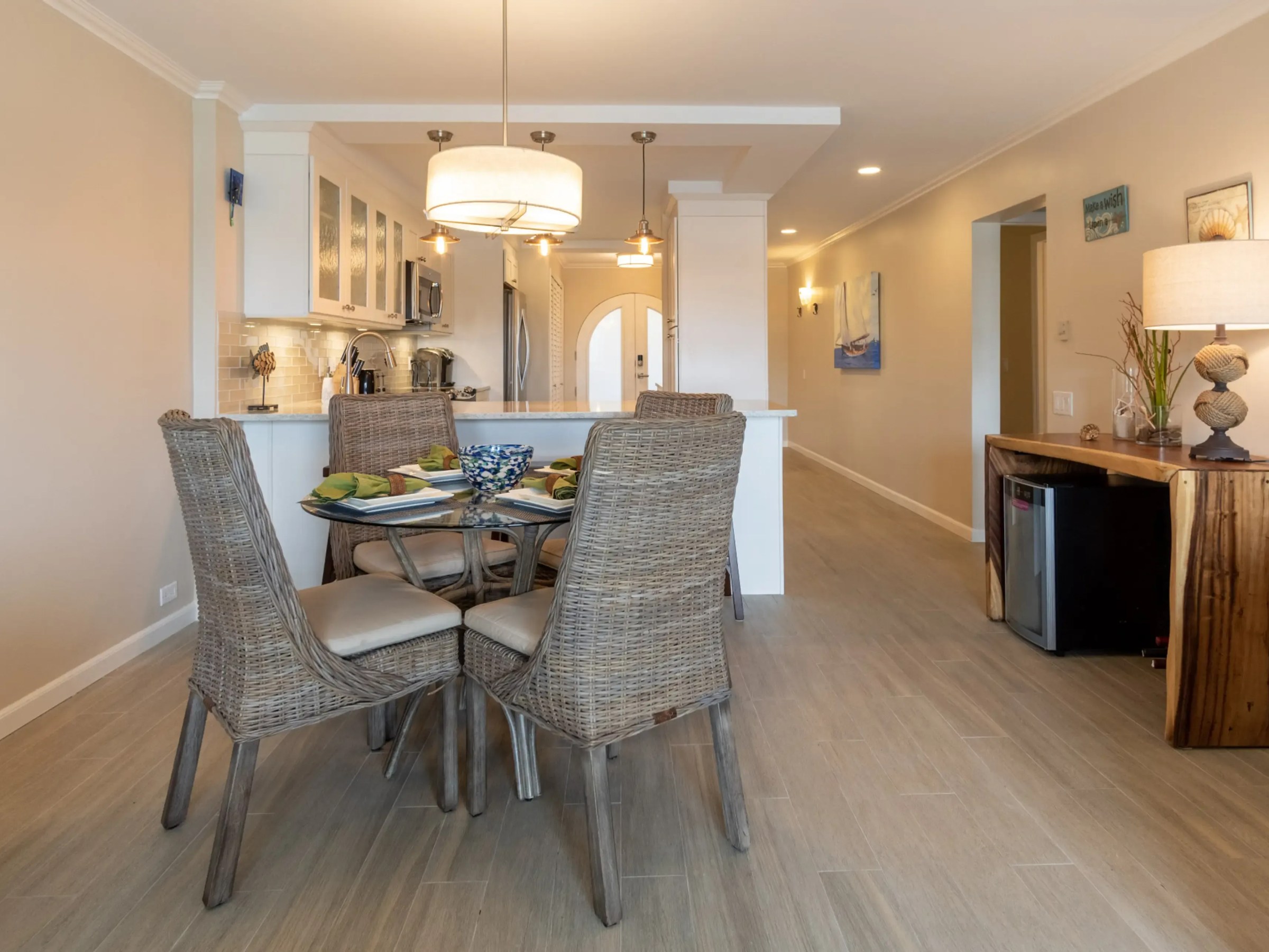 Warm dining room and kitchen with wicker chairs, wooden table, and soft lighting.