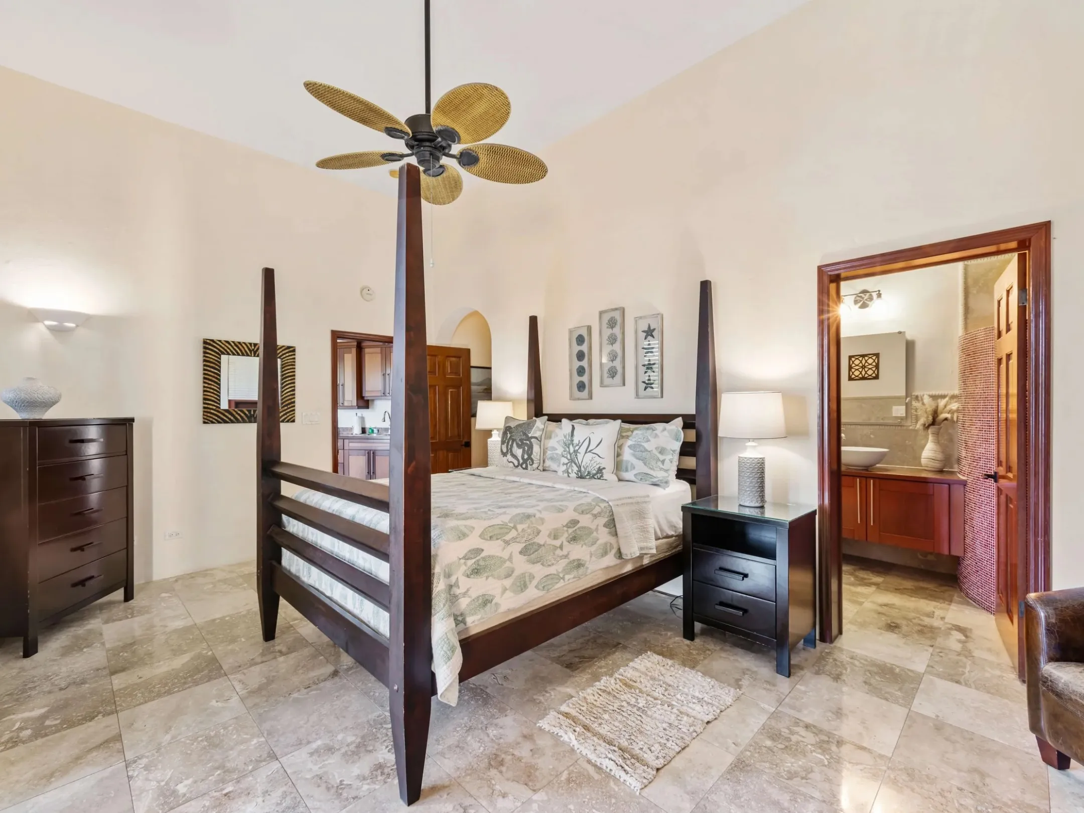 Spacious bedroom with a four-poster bed and ceiling fan, leading to an en-suite bathroom.