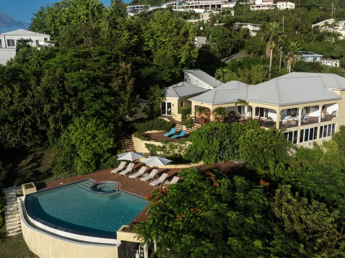 Aerial view of a villa with a pool and lush greenery surrounding it.