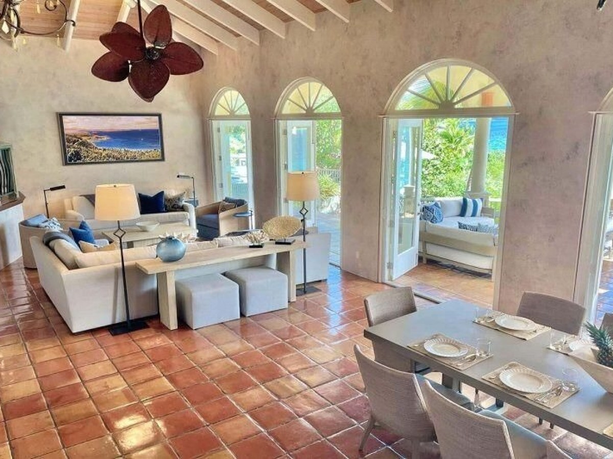 Spacious living-dining room with tiled floor, open doors, ocean view, and modern furniture.