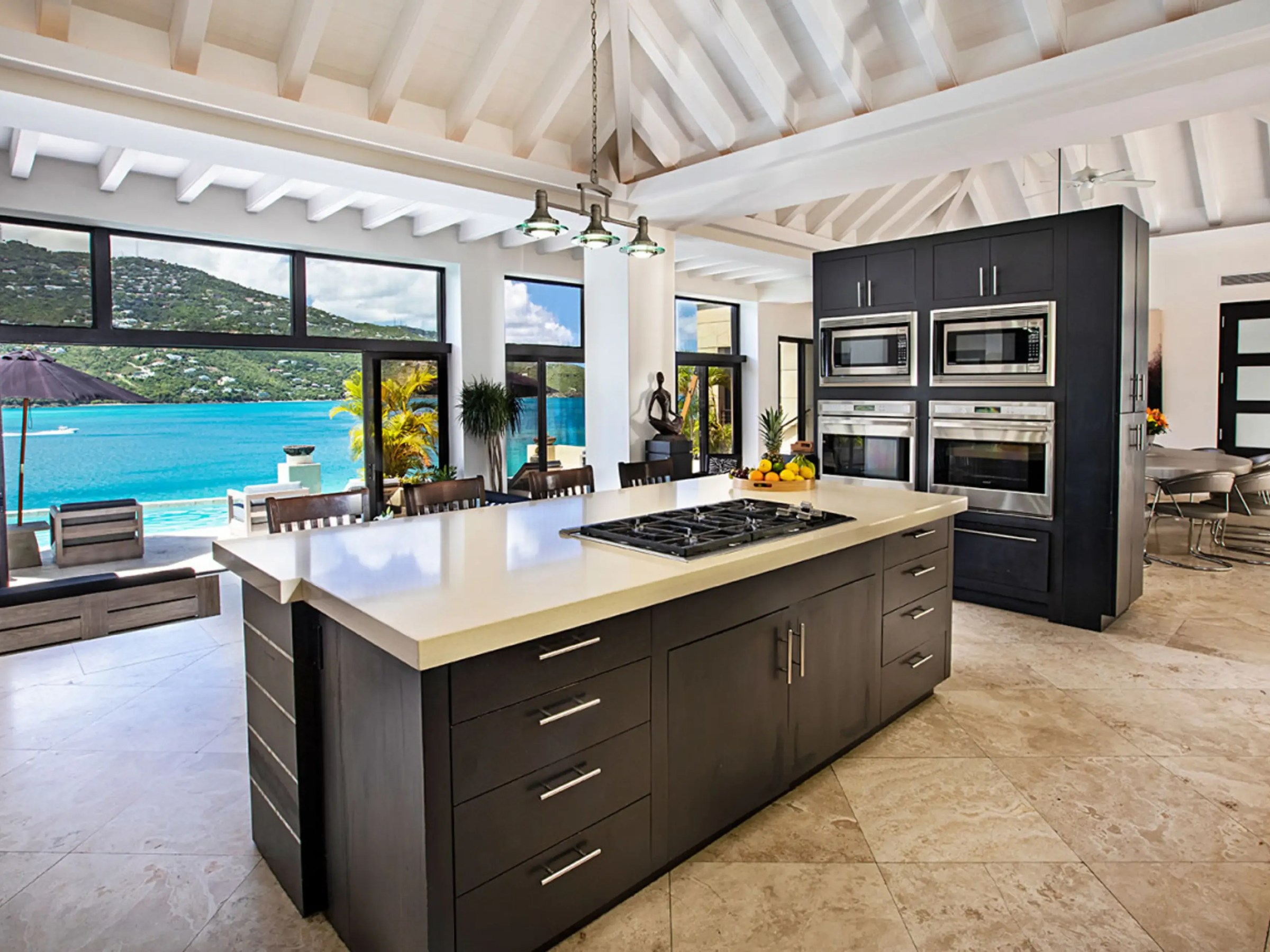Spacious kitchen with island and panoramic ocean view through large windows.