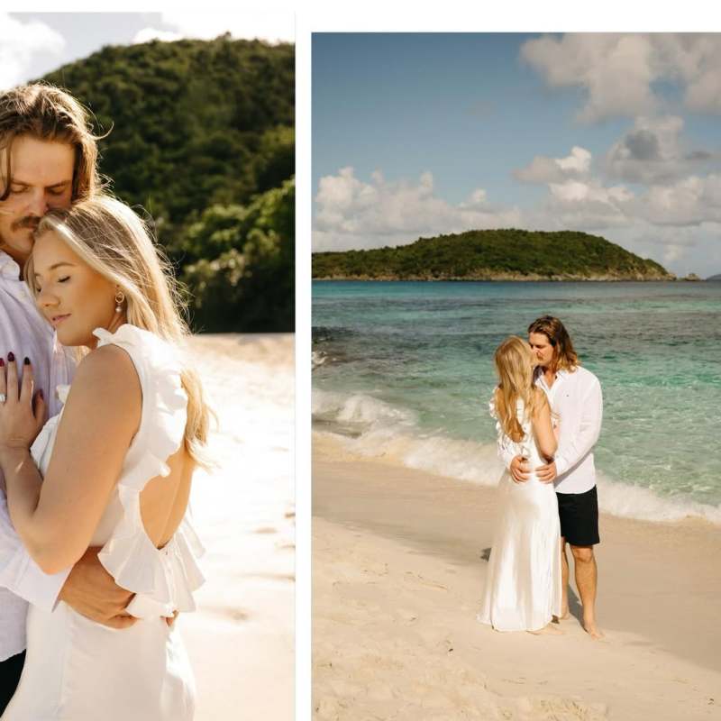 Couple embracing on a sunny beach, gentle waves, and greenery in background.