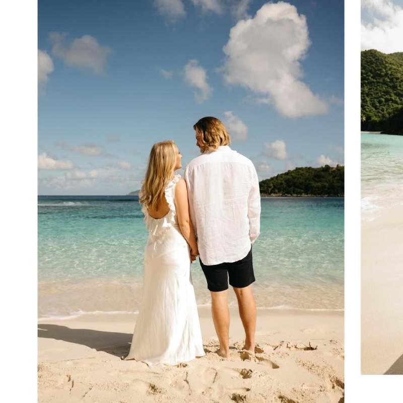 Couple holding hands on a beach, facing the ocean under a clear blue sky.